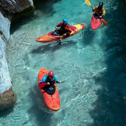 Adventure kayakers paddling through clear turquoise water near Rishikesh