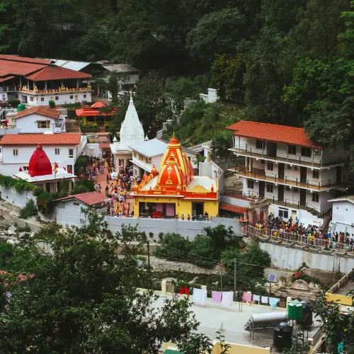 Neem Karoli Baba Ashram at Kainchi Dham surrounded by lush greenery with devotees visiting the temple complex.