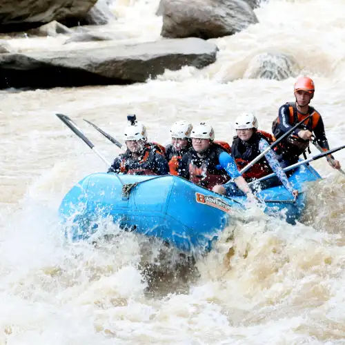 Group enjoying white-water river rafting in Rishikesh on a blue inflatable raft