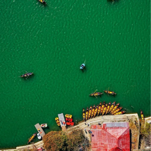 Aerial view of colorful boats on the emerald green waters of Naini Lake in Nainital.