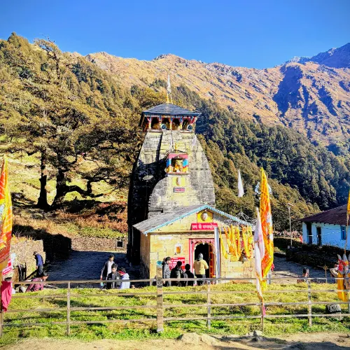 Madmaheshwar Temple surrounded by mountains and clear blue skies, a major Panch Kedar shrine in Uttarakhand.