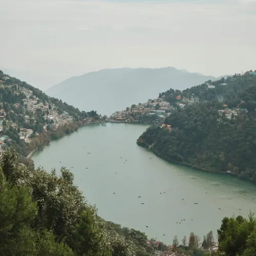 Aerial view of Naini Lake surrounded by green hills and houses in Nainital