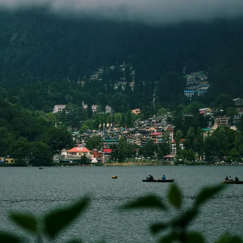 Boats floating on Naini Lake with foggy hills and Nainital town in the background